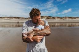 Stock photo of a Kiwi man holding a baby.