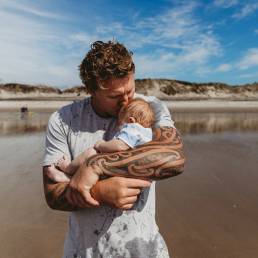 Stock photo of a Kiwi man holding a baby.